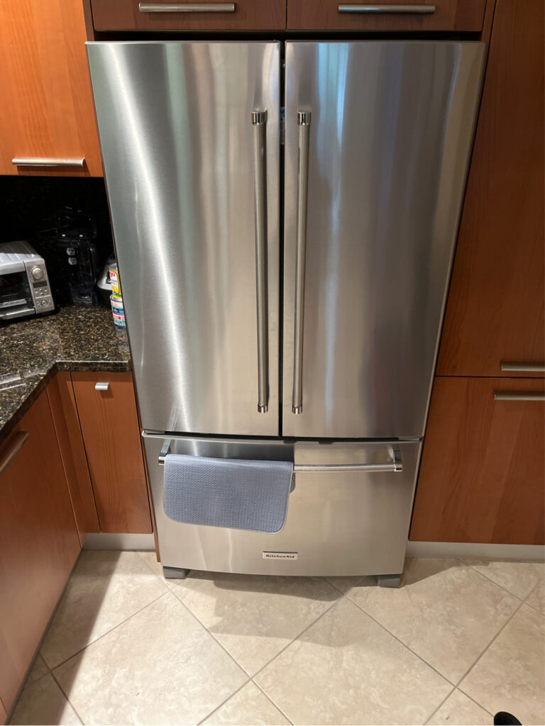 Professional refrigerator repair in Wesley Chapel - Bozmanfix technician servicing a stainless steel French-door refrigerator in a Florida kitchen