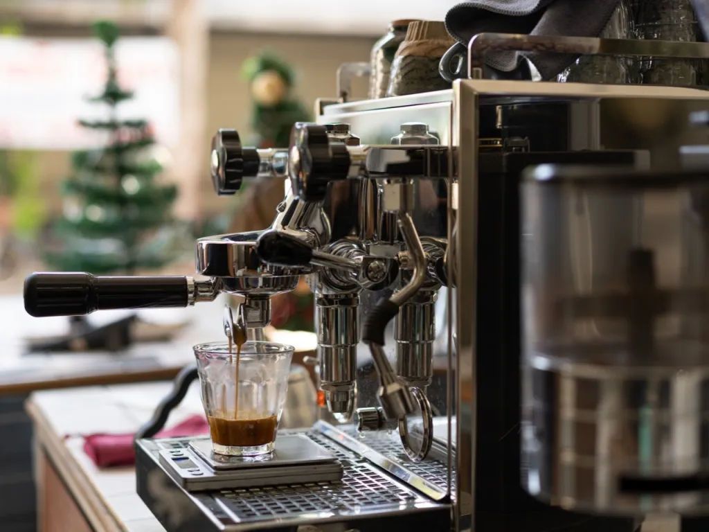 Commercial espresso machine group head pulling a shot